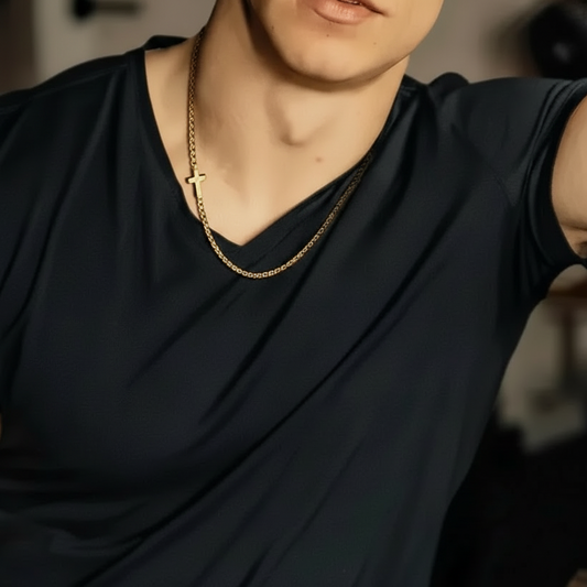 Person wearing a black shirt and gold chain cross necklace with a blurred background