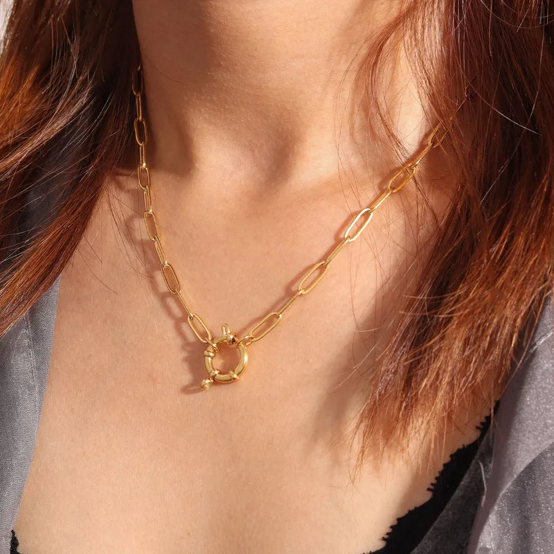 gold spring clasp pendant on paperclip link chain on person with gray and black top