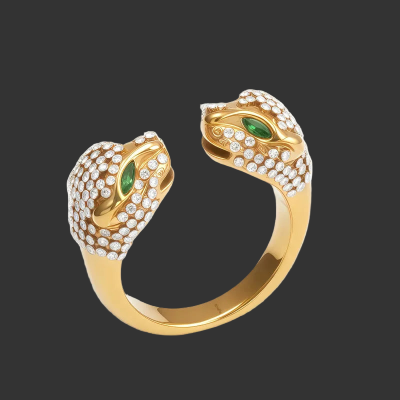 Gold open ring with double panther head design and green stones for eyes with clear stones covering each head on a black background