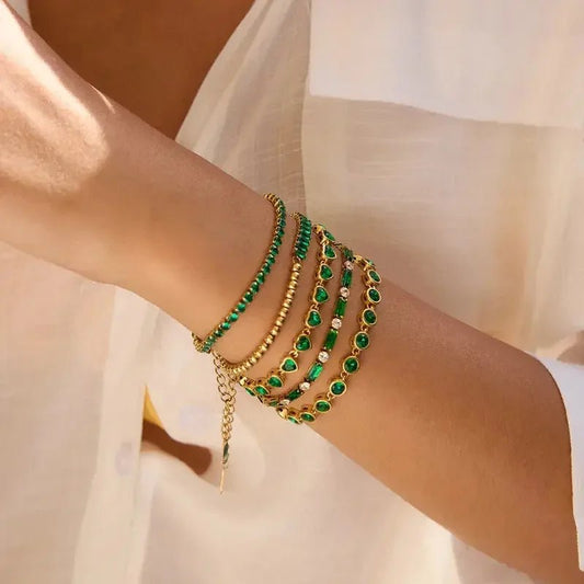 Gold bracelets with green stones stacked on wrist metal content jewelry