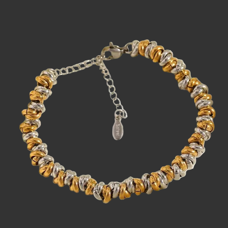 Bracelet with tiny gold and silver rings on a black background