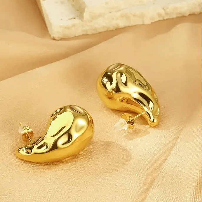 18K gold plated teardrop earrings with a shiny, modern abstract design on beige fabric background