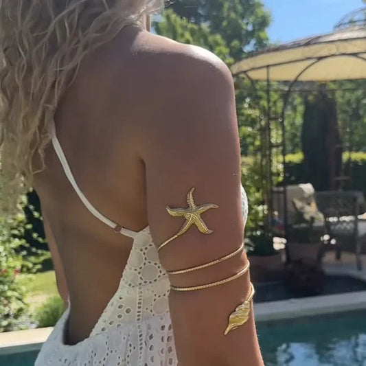 woman wearing jewelry gold arm band with starfish and leaf on the ends
