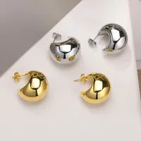 Gold and silver earrings on a white surface