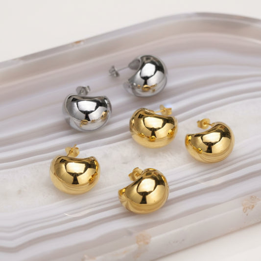Gold and silver earrings on a white surface