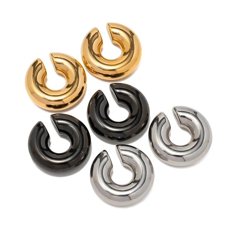 Set of gold, black, and silver large chunky ear cuffs on a white background