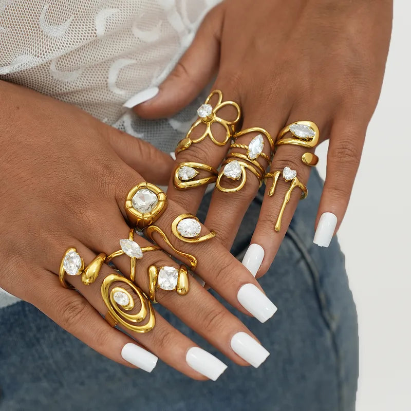 Close-up of hands wearing multiple gold rings with gemstones on a neutral background