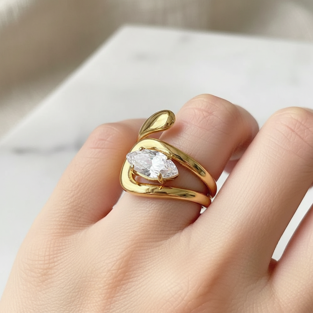Gold horizontal solitaire marquis open ring on a finger against a neutral background