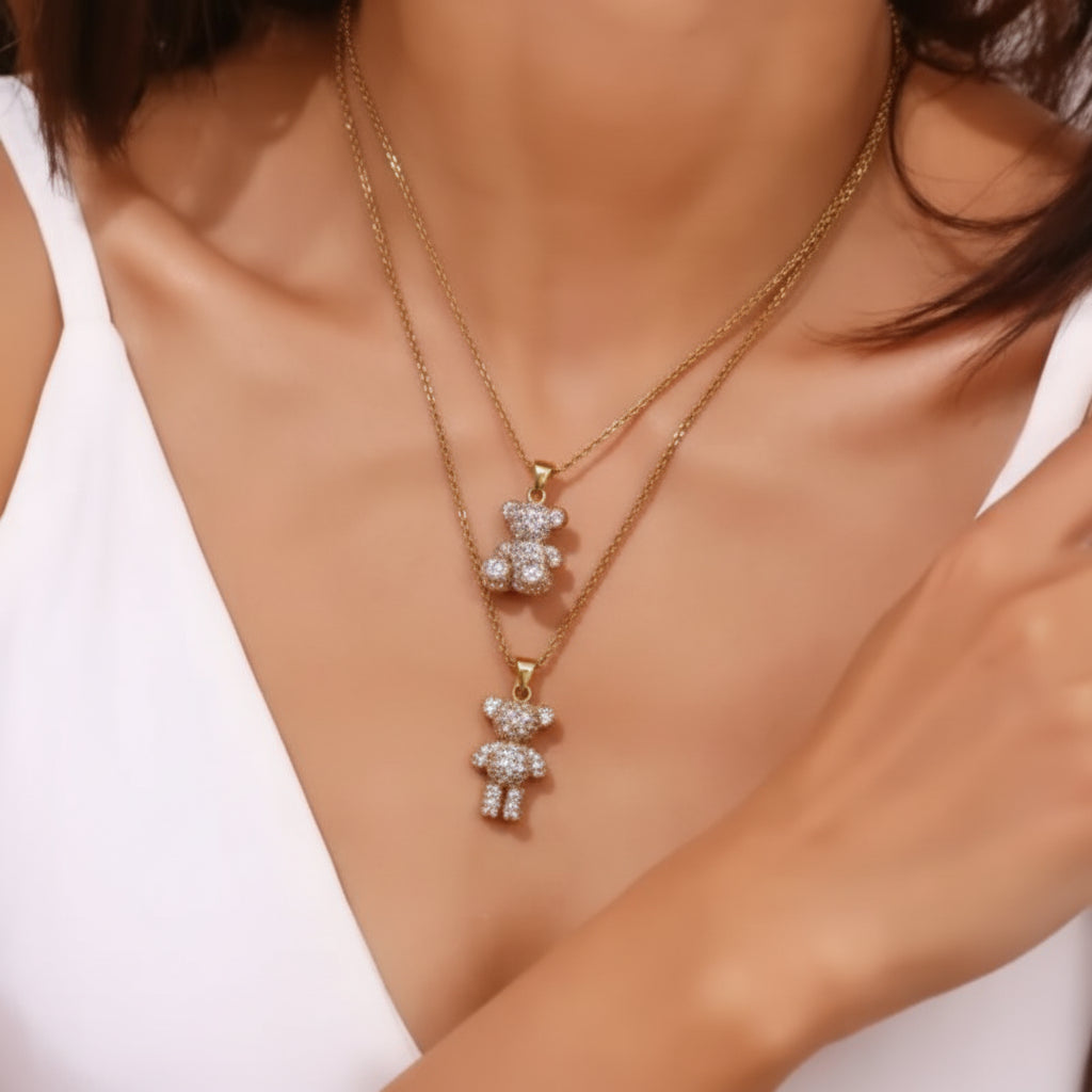 Necklace with a sitting teddy bear pendant and necklace with a standing teddy bear both with inlay stones worn by a person against a white background