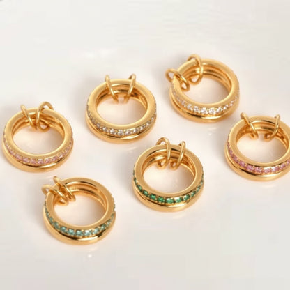 Gold linked rings with various color gemstones on a white background