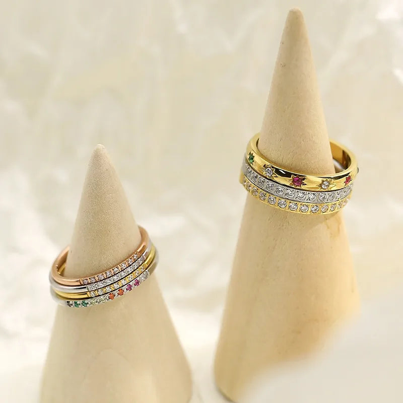 Gold rings with gemstones on beige cone-shaped jewelry stands against a light background