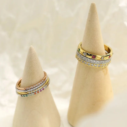 Gold rings with gemstones on beige cone-shaped jewelry stands against a light background