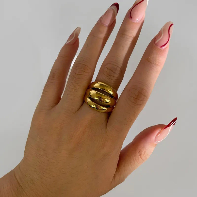 Hand wearing a gold ring with red nail polish on a plain background