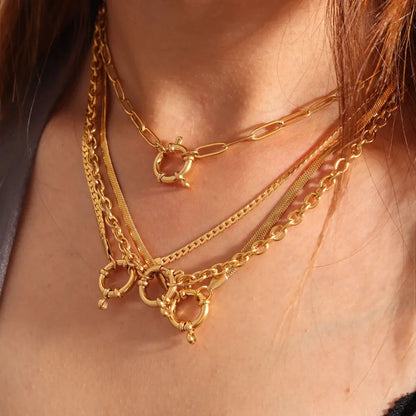 gold spring clasp pendant on several different chain styles on person with gray and black top 