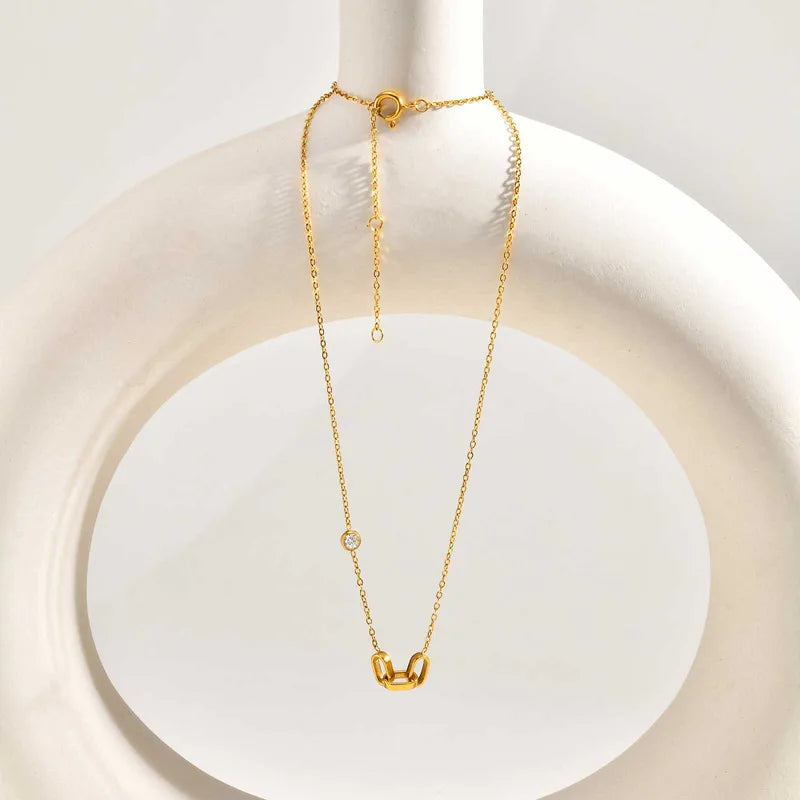 Dainty 3 interlocked links pendant on  a white circular decor piece.