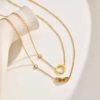 2 gold necklaces one with a gemstone on a circle pendant and one with a 3 interlocked dainty links pendant on a white background