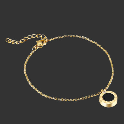 Gold bracelet with a black round charm on a black background
