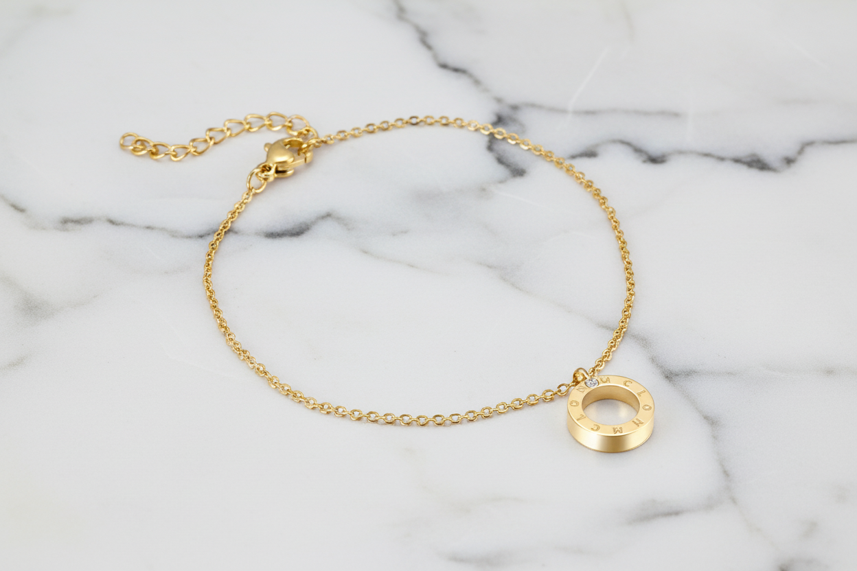 Gold bracelet with a circular pendant on a marble background