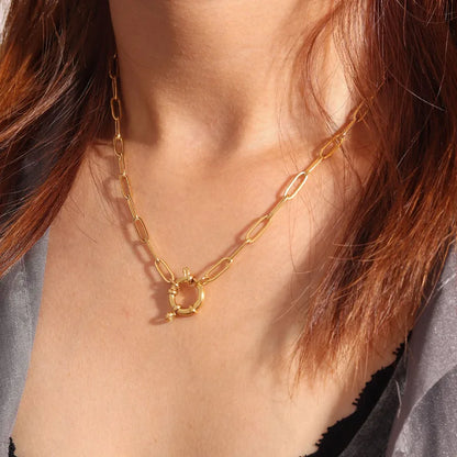 gold spring clasp pendant on paperclip link chain on person with gray and black top