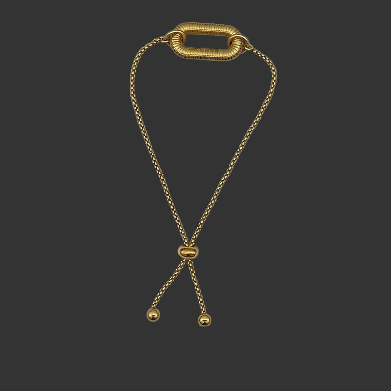 Gold bracelet with carabiner pendant on adjustable chain on a black background