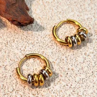 Gold hoop earrings with black accents on a sandy background