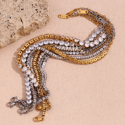 Gold and silver bracelets with clear stones on a beige stone surface