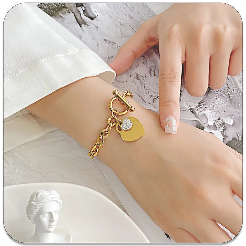 Gold bracelet with heart charms on a wrist against a white background