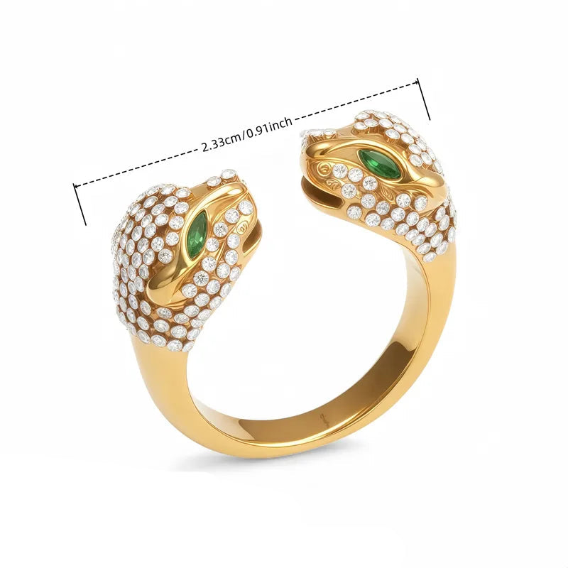 Gold open ring with double panther head design and green stones for eyes with clear stones covering each head on a white background with measurements 