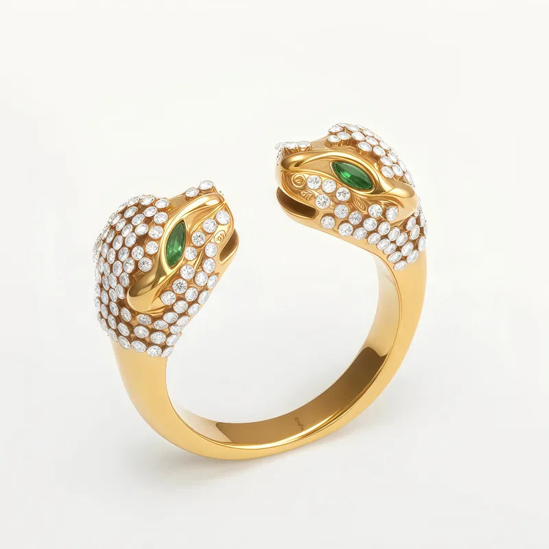 Gold open ring with double panther head design and green stones for eyes with clear stones covering each head on a white background