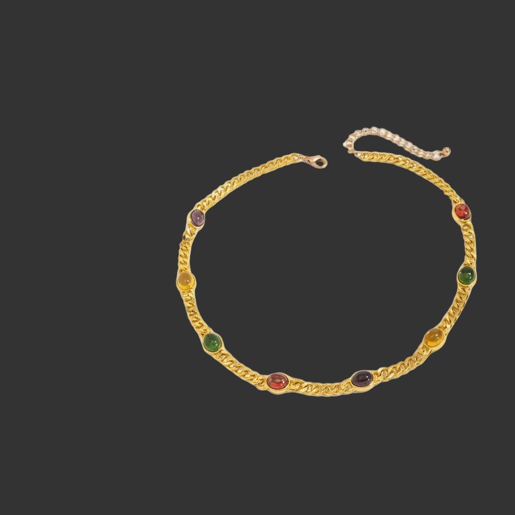 gold necklace with gemstones on black background