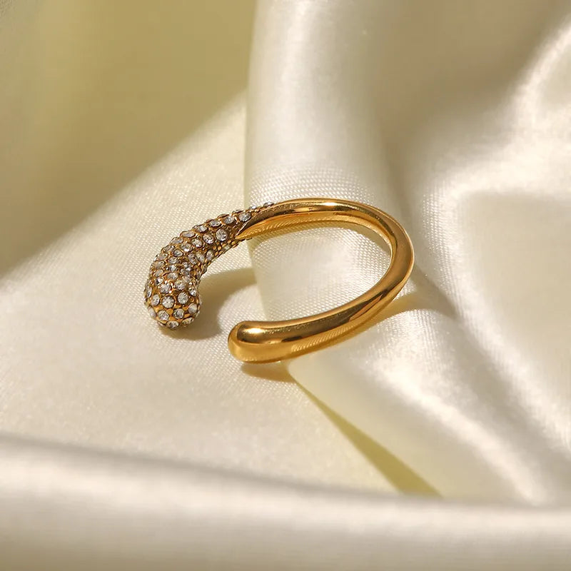 Gold open ring with embedded stones on a beige fabric background