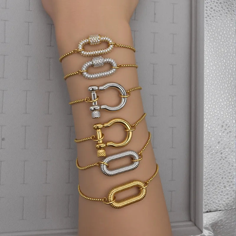 Multiple gold and silver bracelets on a wrist against a neutral background