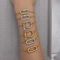 Gold and silver bracelets on a person's wrist against a neutral background