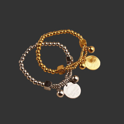 One gold and one silver beaded bracelet on a black background.