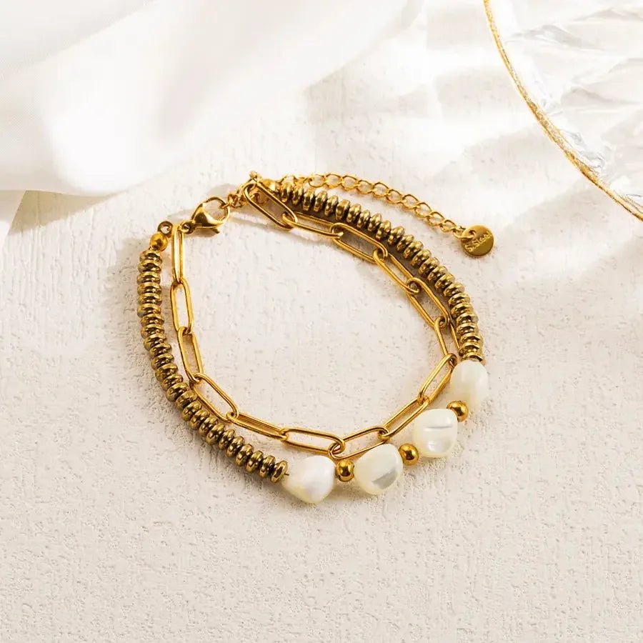 Gold tone stainless steel link bracelet with pearls and adjustable chain clasp on light background