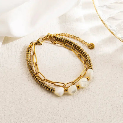 Gold tone stainless steel link bracelet with pearls and adjustable chain clasp on light background