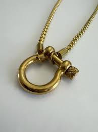 Gold horseshoe lock bracelet with close up of lock on a gray background