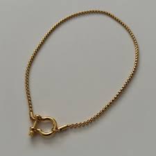 Gold horseshoe lock bracelet on a gray background