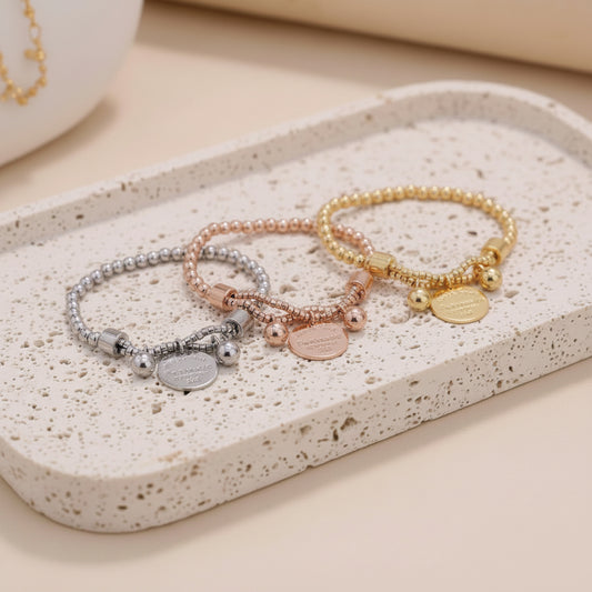 Set of three bracelets in different colors with engraved text on a white background