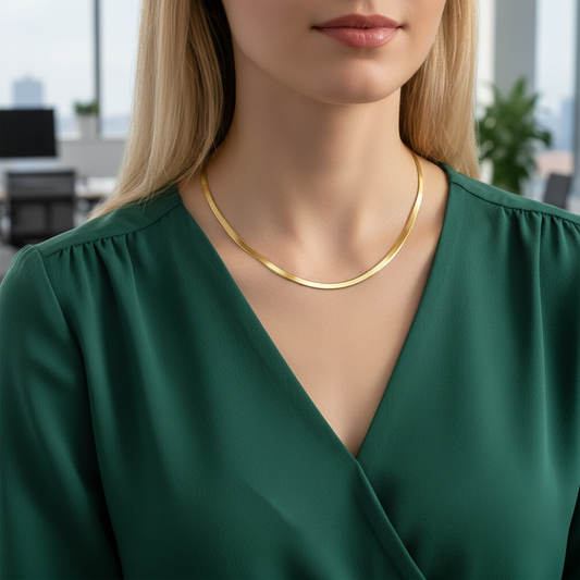 Woman wearing a gold necklace with a blurred office background