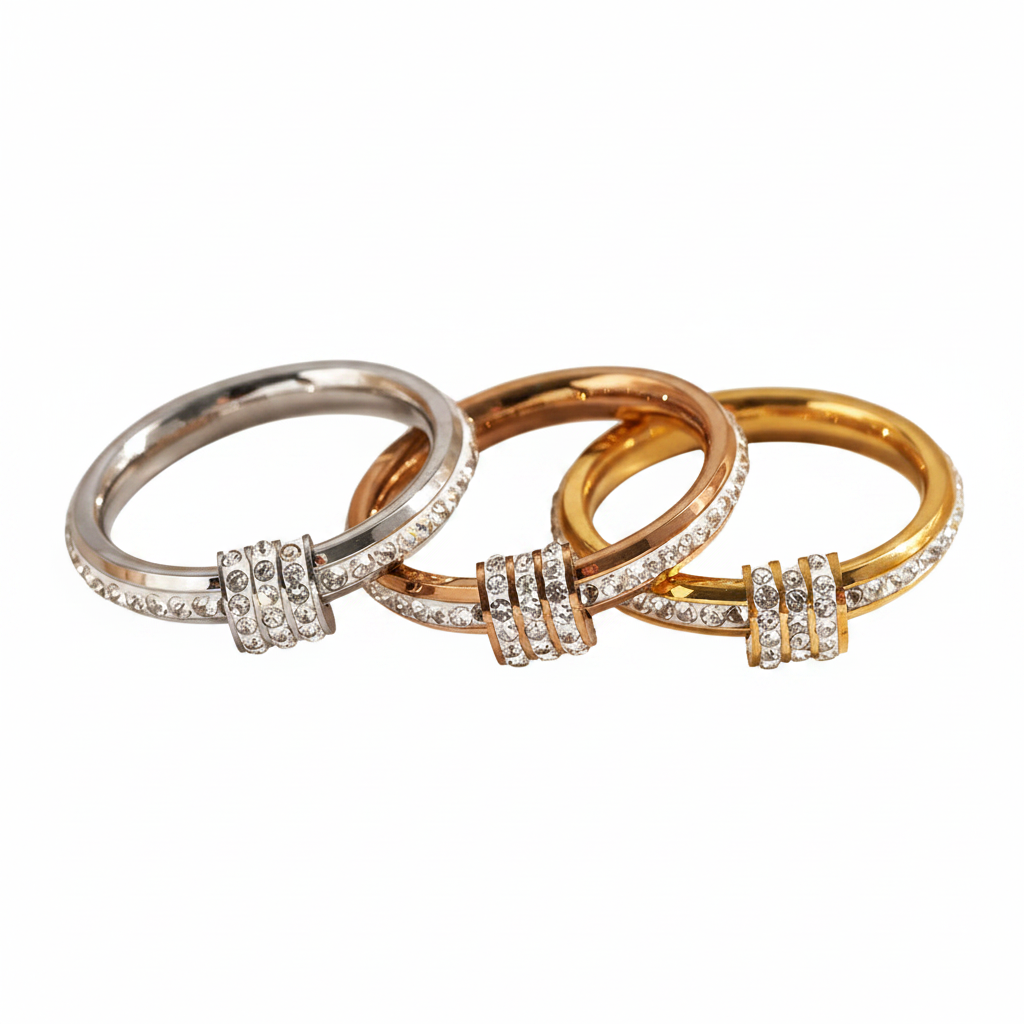 Three interlocking rings in silver, yellow gold, and rose gold, each featuring a central cluster of small clear stones, shown on a plain white background.