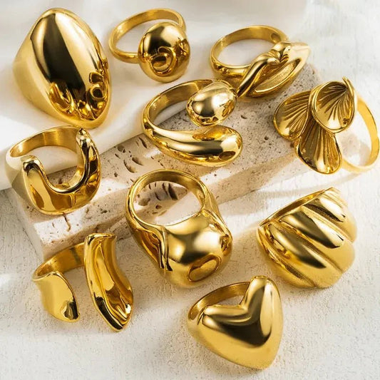 multiple gold rings with various designs on stone background